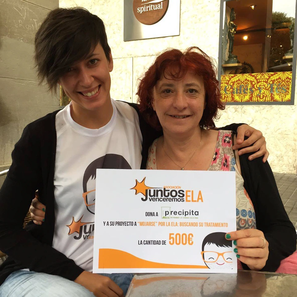 dos mujeres con cheque de donación de Juntos Venceremos ELA